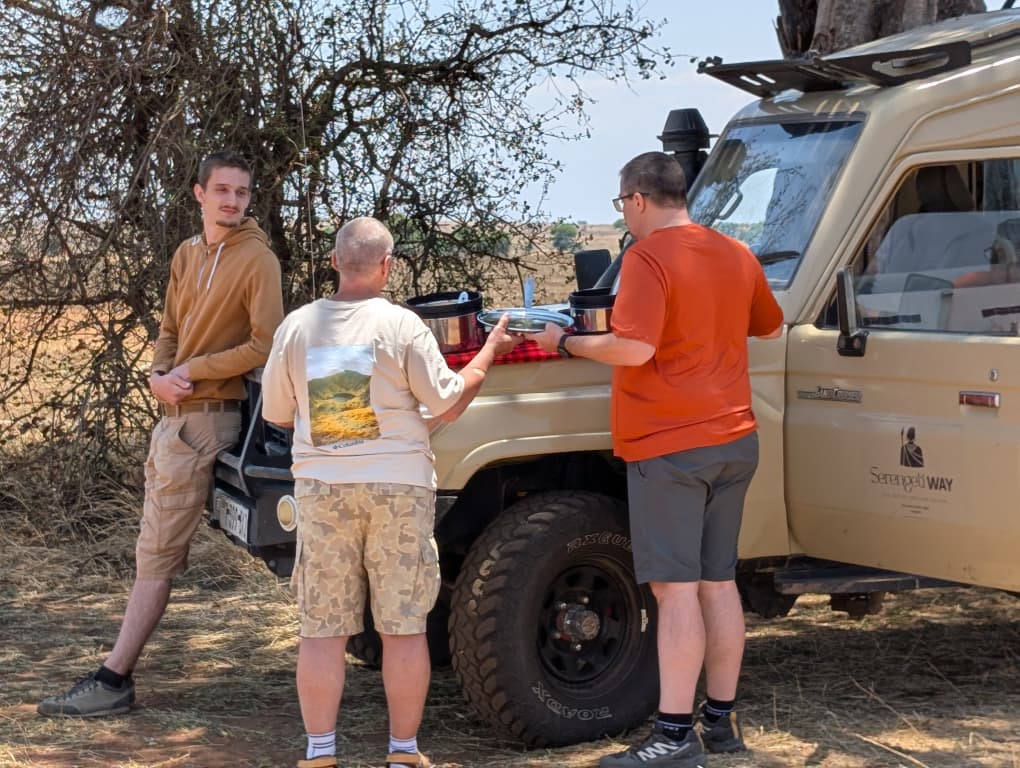 Safari guests beside a Serengeti Way vehicle